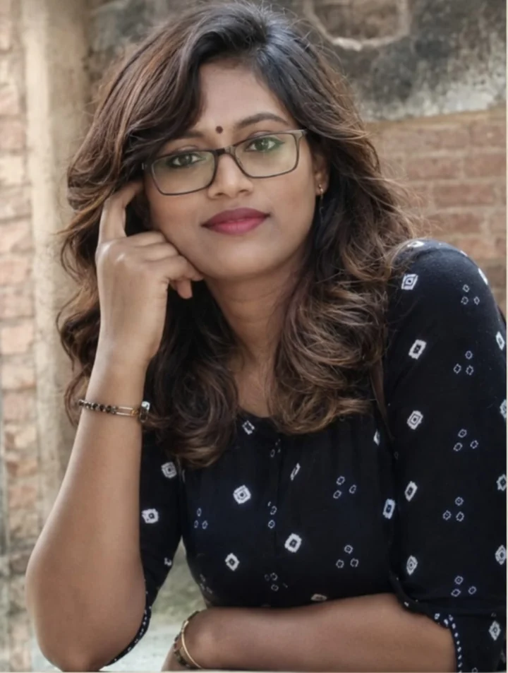 Savita Anand, smiling, wearing glasses and a dark printed kurta